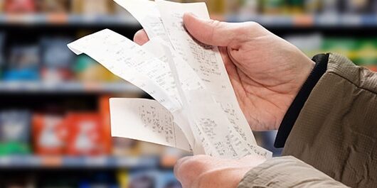 cost-of-living-banner Man reading shopping receipt