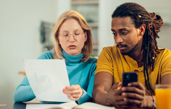 male and female sitting next to each other, female holding piece of paper which both are looking at