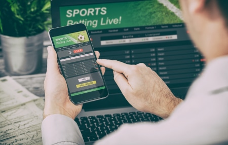 How-to-deal-with-gambling-debt-feature person placing a bet online on smartphone