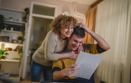 What-happens-at-the-end-of-an-IVA_-Feature Woman hugging man reading letter and smiling