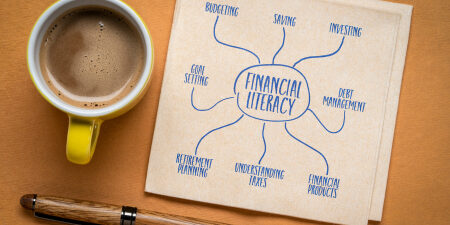 An image of 'financial literacy' on a piece of paper next to a pen and a coffee