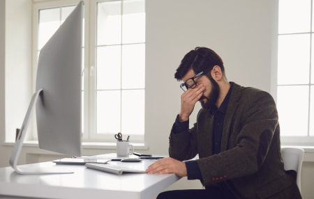 How-Debt-could-Affect-Your-Career-feature Man sat at a desk with his head in his hands.