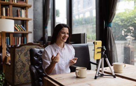 The-Rise-of-Gig-Work-feature An image of a woman sitting at her desk filming content for social media.