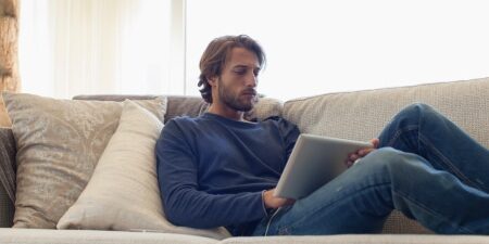 Image of man laying on the sofa looking at his iPad