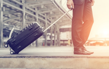 Can-I-move-abroad-with-debt-feature An image of a man pulling a suitcase towards the airport.