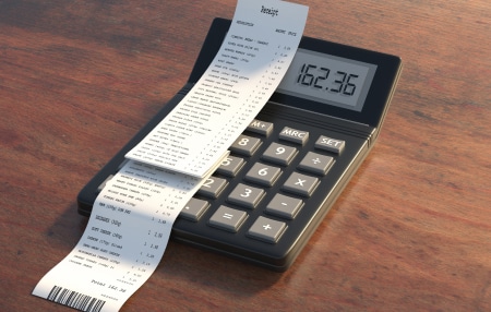 How-to-Deal-with-Unexpected-Expenses-feature Image of a calculator on a wooden desk with a receipt on top