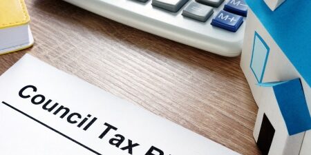 How-to-Write-off-Council-Tax-Debt-feature Image of a computer keyboard on a wooden desk with a council tax bill letter.