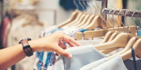 How to save money clothes shopping feature Image of someone searching through a clothes rack in a shop