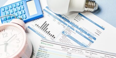 Image of bills, a light bulb, an alarm clock and a calculator