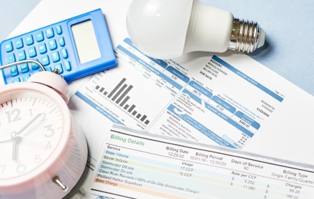 What happens if you can’t pay your energy bills feature Image of bills, a light bulb, an alarm clock and a calculator