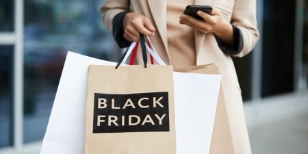 Black Friday and Cyber Monday_ How To Not Be Tempted feature Image of a woman holding a few Black Friday shopping bags.