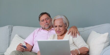 Does my partners debt affect my credit score_ feature Image of a woman and a man sitting on the sofa looking at their laptop.