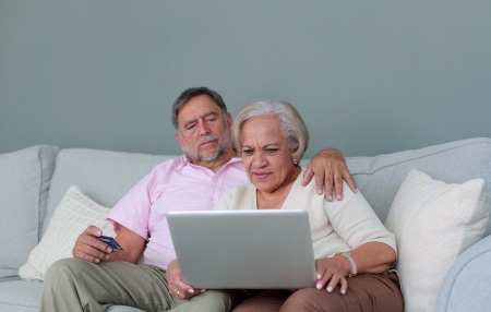 Does my partners debt affect my credit score_ feature Image of a woman and a man sitting on the sofa looking at their laptop.