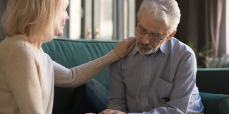 Image of a woman comforting her husband on the sofa