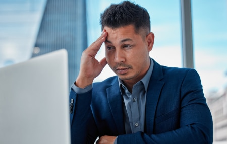 Stress Awareness Day_ Ways to Reduce Debt and Worry feature Image of a man with his head in his hands looking at his laptop screen