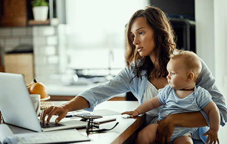 woman 1 Imagine of a woman on her laptop whilst holding her baby