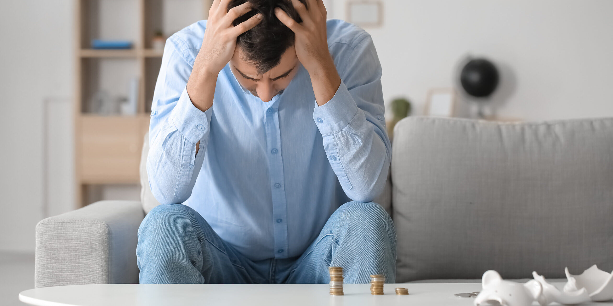 Man sat on a couch stressed about money