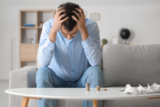 Man sat on a couch stressed about money