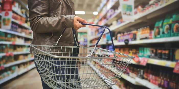 Cropped shot of a woman holding a basket while shopping at a grocery store